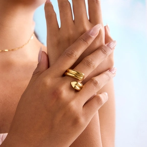 Nahaufnahme eines goldenen Wickelrings im Wellendesign am Finger mit Hochglanz-Finish