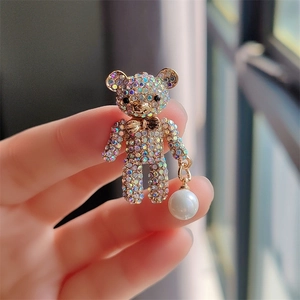 Detailed view of a sparkling teddy bear brooch with colorful rhinestones and a white pearl