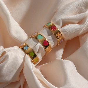 Detailed macro shot of gold-plated rings with colorful enamel star, heart and smile patterns