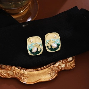 Detail of vintage French enamel earrings with pearls and gold leaf on a retro frame
