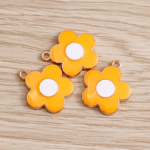Macro shot of orange enamel daisy charms with gold metal edges and white centers