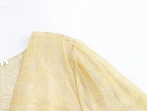 Détail du décolleté en V en jacquard jaune avec manche lanterne et étiquette S