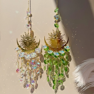 Detail of sun and moon crystal suncatchers casting colorful shadows on a neutral wall