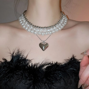 Gros plan sur un collier de perles multicouches avec pendentif cœur en argent poli