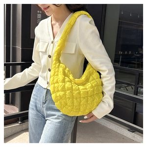 Detail of bright yellow quilted cloud bag with plush diamond padding and wide strap