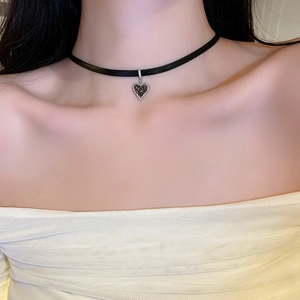 Close-up of black ribbon choker necklace with dark crystal heart pendant on model
