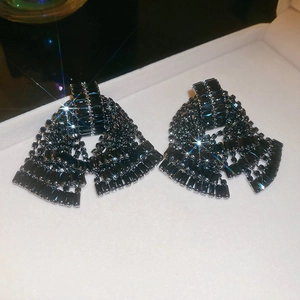 Macro view of crystal bow tassel earrings with sparkling black rhinestones on white display