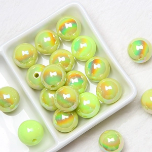 Macro shot of 16mm light green iridescent acrylic beads in a ceramic tray for DIY jewelry