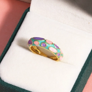 Détail de points en émail coloré sur bague ajustable dorée dans un écrin
