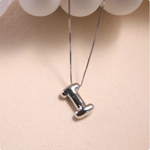 Close-up of polished silver letter I pendant on a durable box chain necklace