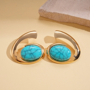 Macro shot of gold spiral alloy earring with blue faux stone on a textured background