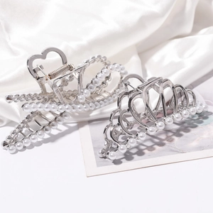 Detail of silver metal hair claws with white pearls and heart cut-out on white silk