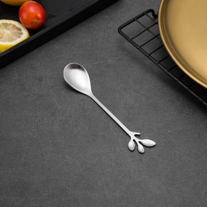 Detailed top view of a silver leaf-shaped handle spoon on a rustic stone tabletop decor