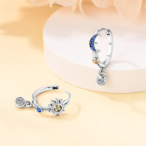 Detailed view of silver crescent moon and star earrings with blue and yellow gemstones