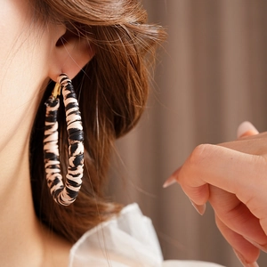 Close-up of model wearing retro leopard print round hoop earrings with golden needles