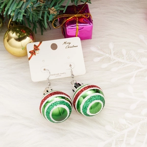 Detail of glitter striped Christmas ball earrings on festive plush background