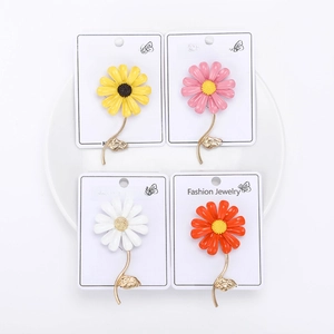 Detail of four colorful enamel daisy brooches in yellow, pink, white, and orange