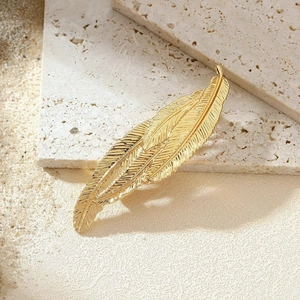 Vintage golden metal feather hair clip on stone background with natural sunlight