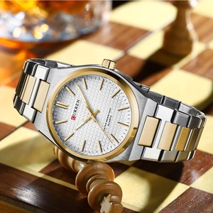 Detail of a two-tone quartz watch with white dial placed on a luxury chess set