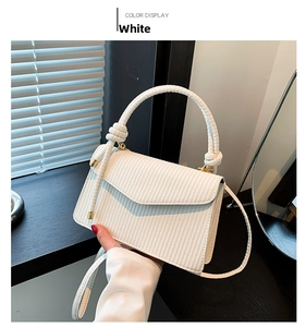 Close-up of white PU crossbody bag with woven texture and decorative knot handle detail