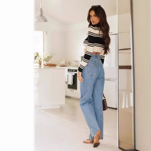 Women's blue high-waist wide-leg jeans with striped long-sleeve crop top in a modern kitchen
