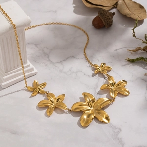 Elegant gold flower necklace with blooming petals on marble stone for women