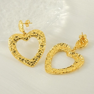 Dettaglio degli orecchini a cuore in oro 18k con una trama a martello e ondulata