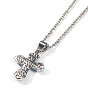 Macro detail of silver cross pendant with honeycomb texture and polished curb chain