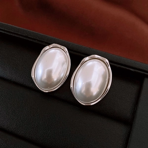 Macro shot of French oval pearl earrings with liquid metal silver frame on black base