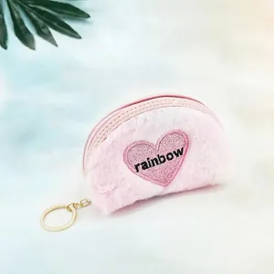 Close-up of pink plush heart coin purse with rainbow embroidery and gold keychain