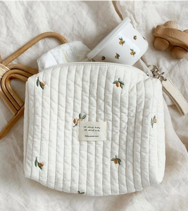 Detailed macro view of embroidered citrus patterns on quilted cotton baby organizer bag