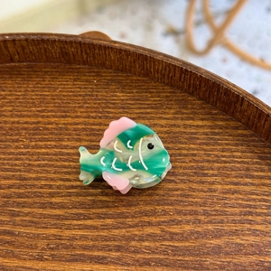 Vue détaillée d'une pince à cheveux en acétate marbré vert en forme de poisson mignon