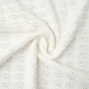 Detailed macro shot of white pointelle knit fabric with geometric triangular hollow patterns