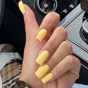 Uñas postizas rectangulares amarillas de longitud media puestas en la mano en coche