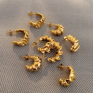 Detail of assorted 18k gold plated stainless steel C-shaped earrings with textured patterns