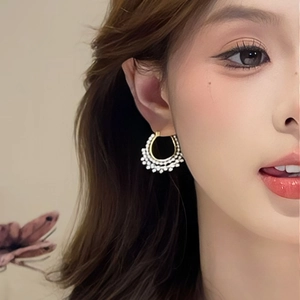 Close-up of elegant gold twisted hoop earrings with double-row white pearls on model