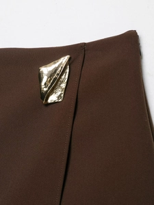Detailed macro view of dark brown skirt waist featuring irregular gold metal hardware