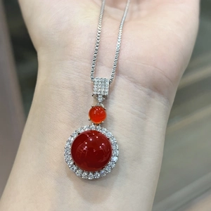 Detailed close-up of a silver necklace with round red chalcedony pendants on a wrist