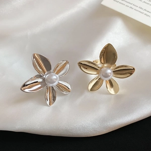 Macro detail of metallic flower ring with a white pearl on elegant white silk background