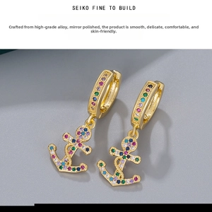 Macro shot of anchor-shaped drop earrings with colorful zircon stones in gold finish