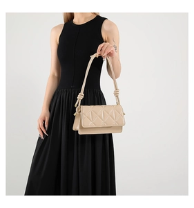 Detail of beige shoulder bag with geometric quilted pattern and knotted strap detail