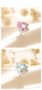 Close-up of heart-shaped pink and blue zircon earrings on elegant champagne silk fabric