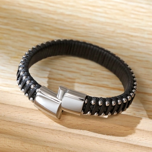 Close-up of black braided leather bracelet with metal studs on a wood block