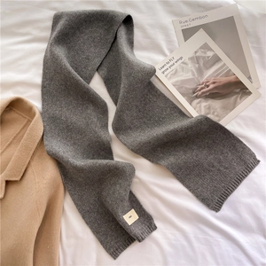 Detailed texture of thick grey knit scarf with ribbed edge and minimalist woven tag