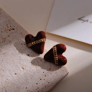 Macro view of heart-shaped glazed earrings with decorative golden metal chain