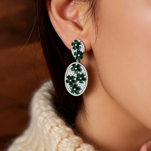 Detail of vintage silver needle earrings with green zircon flower and white rhinestones