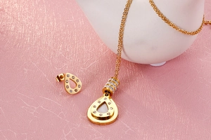 Detail of gold teardrop necklace and earrings set with inlaid cubic zirconia