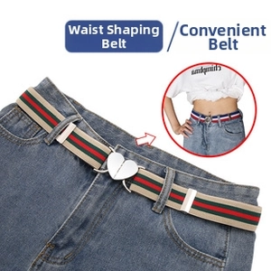 Detail of adjustable waist buckle with green and red striped elastic band on denim jeans