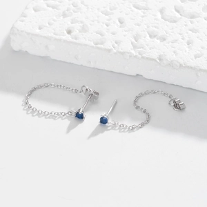 Macro view of sterling silver chain earrings with deep blue circular gemstones and fine chains