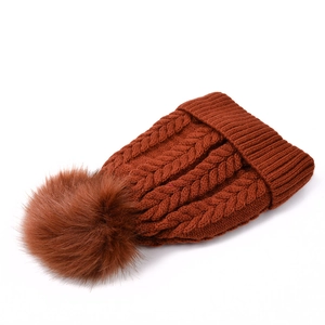 Détail du tricot torsadé marron foncé et du pompon doux sur le bonnet d'hiver chaud